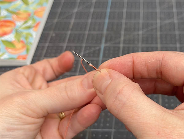 move the thread down the shaft of the needle until it reaches the eye